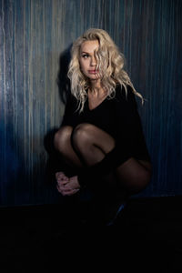 Beautiful woman sitting against wall