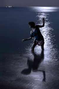 Woman standing in sea at night