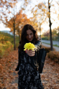 Young woman standing by yellow flower on tree