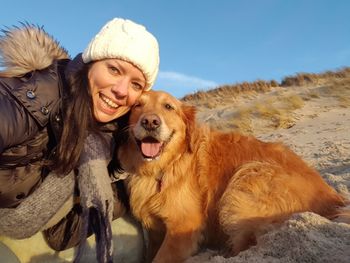 Portrait of smiling boy with dog against sky