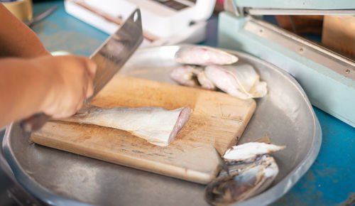 Chef cuts fillet into pieces on a wood cutting board and prepare ingredients in the kitchen.