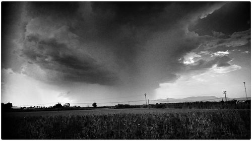 Scenic view of grassy field against cloudy sky