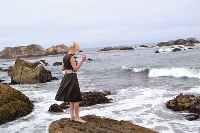 Woman photographing sea against sky