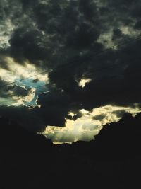 Low angle view of silhouette trees against cloudy sky