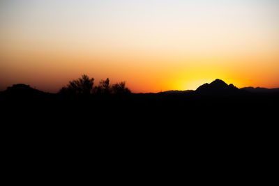 Silhouette landscape against clear sky during sunset