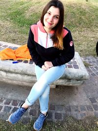 Portrait of smiling young woman sitting on land