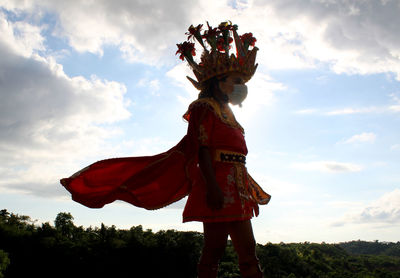 Low angle view of person standing by tree against sky