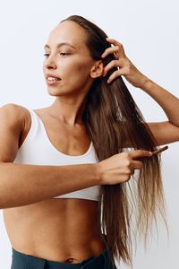 Portrait of young woman standing against white background