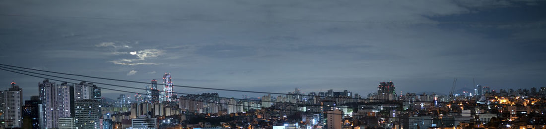 Panoramic view of illuminated buildings against sky at night