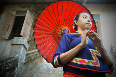 Low angle view of young woman standing against multi colored wall