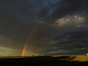 Rainbow over landscape against cloudy sky