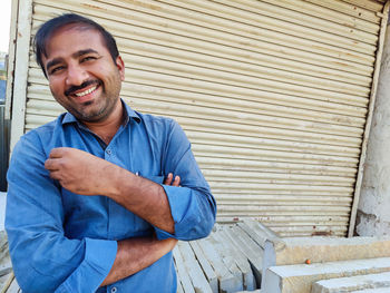 Portrait of smiling young man standing against wall