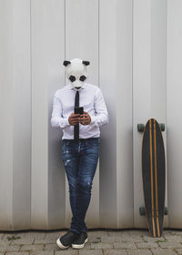 Person wearing mask standing against wall