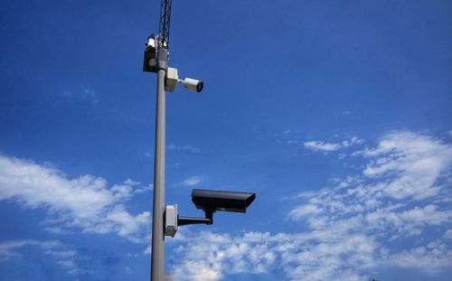 Low angle view of security cameras against blue sky