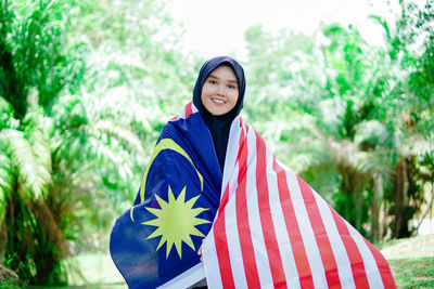 Muslim woman happy holding a malaysian flag. malaysia independence day.