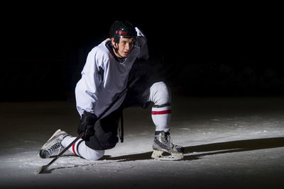 Man playing ice hockey against black background