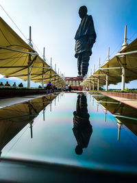 Reflection of people on swimming pool in lake against sky