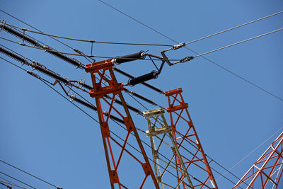 Low angle view of electricity pylon against clear blue sky