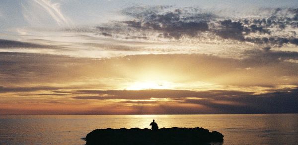 Silhouette people on beach against sky during sunset