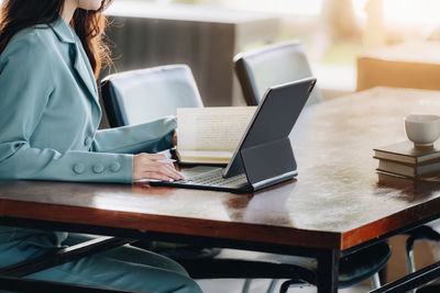 Midsection of woman using laptop on table