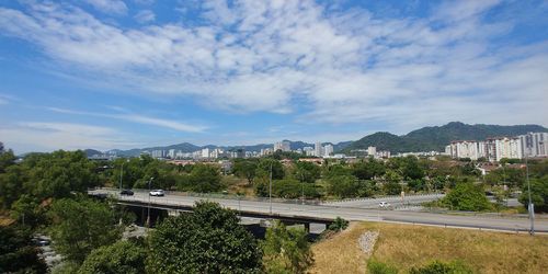 Road by buildings in city against sky