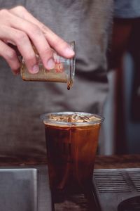 Close-up of hand holding drink on table