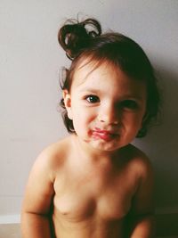 Close-up portrait of topless girl against wall