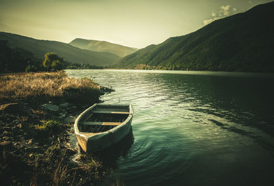 Boat moored on lake against sky