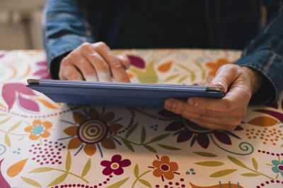 Midsection of man holding mobile phone on table