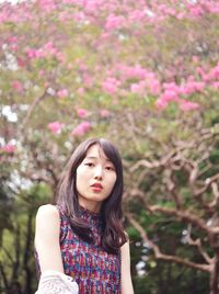 Portrait of beautiful young woman standing against plants