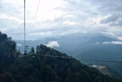 Overhead cable car over mountains against sky