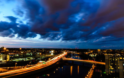 Light trails on road in city against sky at night