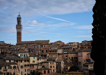 Buildings in town against cloudy sky