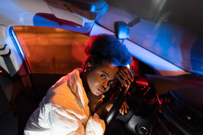 Tired african woman lying on steering wheel, sad depressed black female sitting in car at night