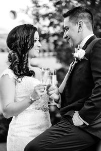 Smiling bride and groom toasting champagne flutes while standing outdoors