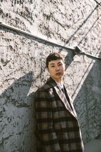 Portrait of young man standing against wall