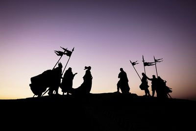 Silhouette people on land against clear sky during sunset