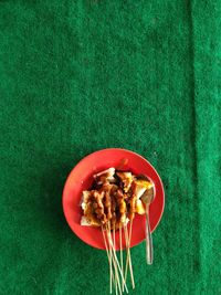 Chicken satay on a green carpet background