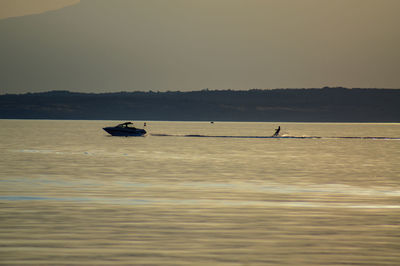 Silhouette men in sea against clear sky