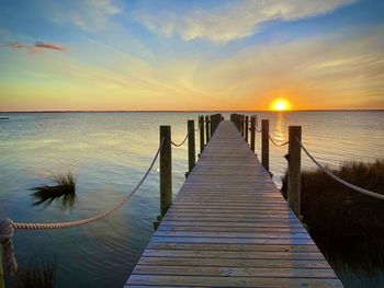Wooden pier over sea against sky during sunset