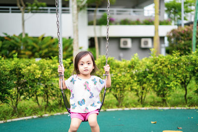 Active little toddler child playing swing at the playground. happy and fun time.