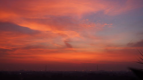 Silhouette buildings against dramatic sky during sunset