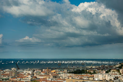 Aerial view of town by sea against sky