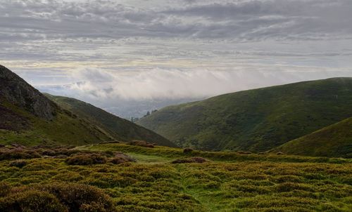 Scenic view of mountainous landscape against mist and sky 