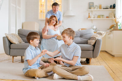 Happy family spend free time in living room, young parents are relaxing on sofa