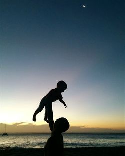 Silhouette of people on beach at sunset