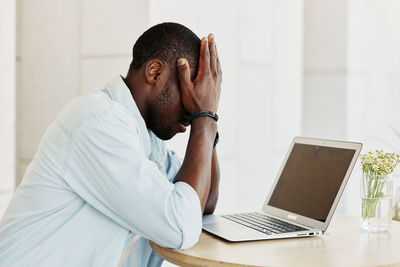 Side view of man using laptop at home