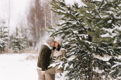 A man and a woman in love walk in a snowy forest among trees in the winter countryside in nature