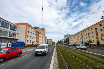 Cars on street amidst buildings in city against sky