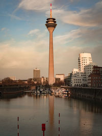 City at waterfront against cloudy sky